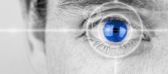 27554617 - vision concept with a greyscale image of a mans eye with a crosshair focused on his iris which has been selectively colored blue.